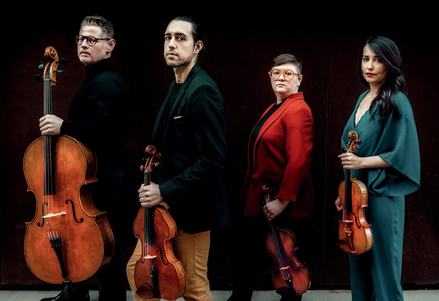 The four musicians of the Catalyst Quartet face to the left against a black background, each holding their instruments -- from left to right, cello, viola, violin, violin.